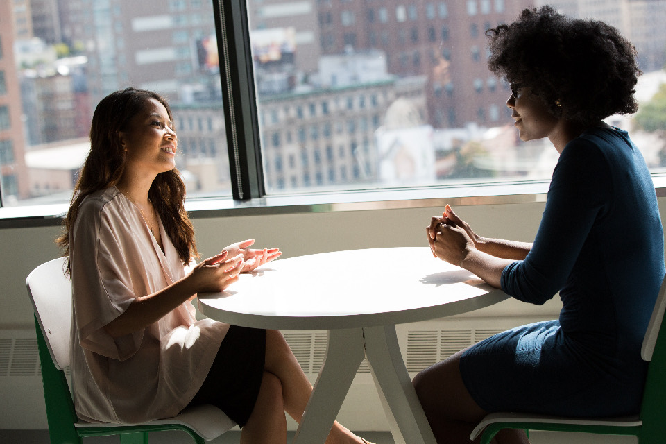 Two women talking across a table in an office