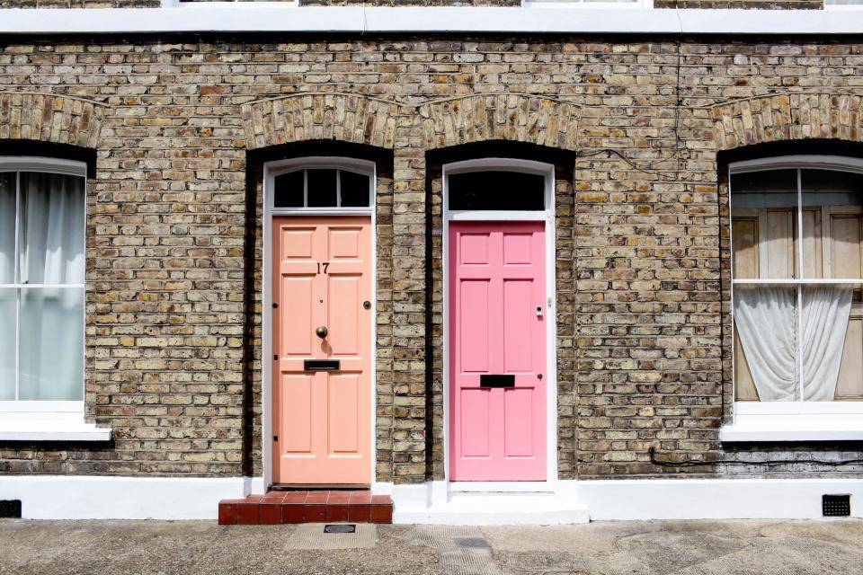 A row of brick terraced houses with colourful front doors