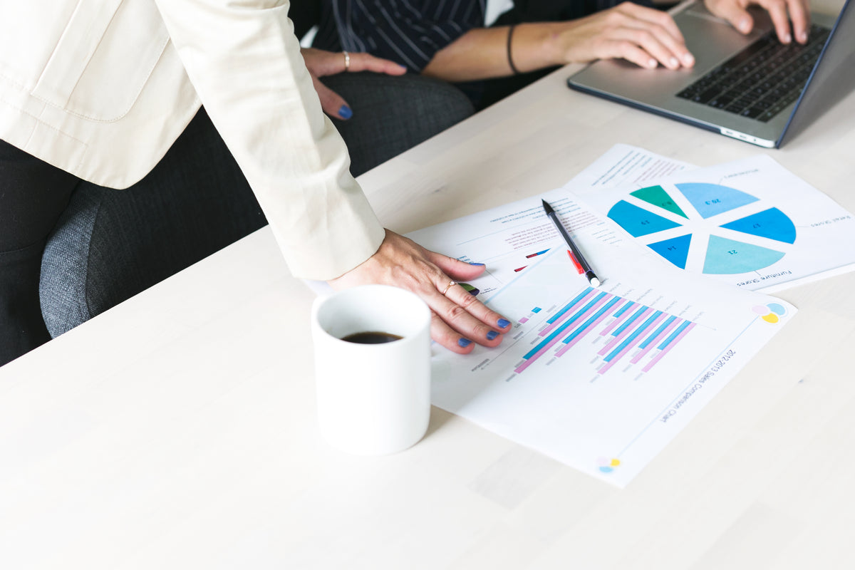 Printed financial charts being reviewed beside a laptop