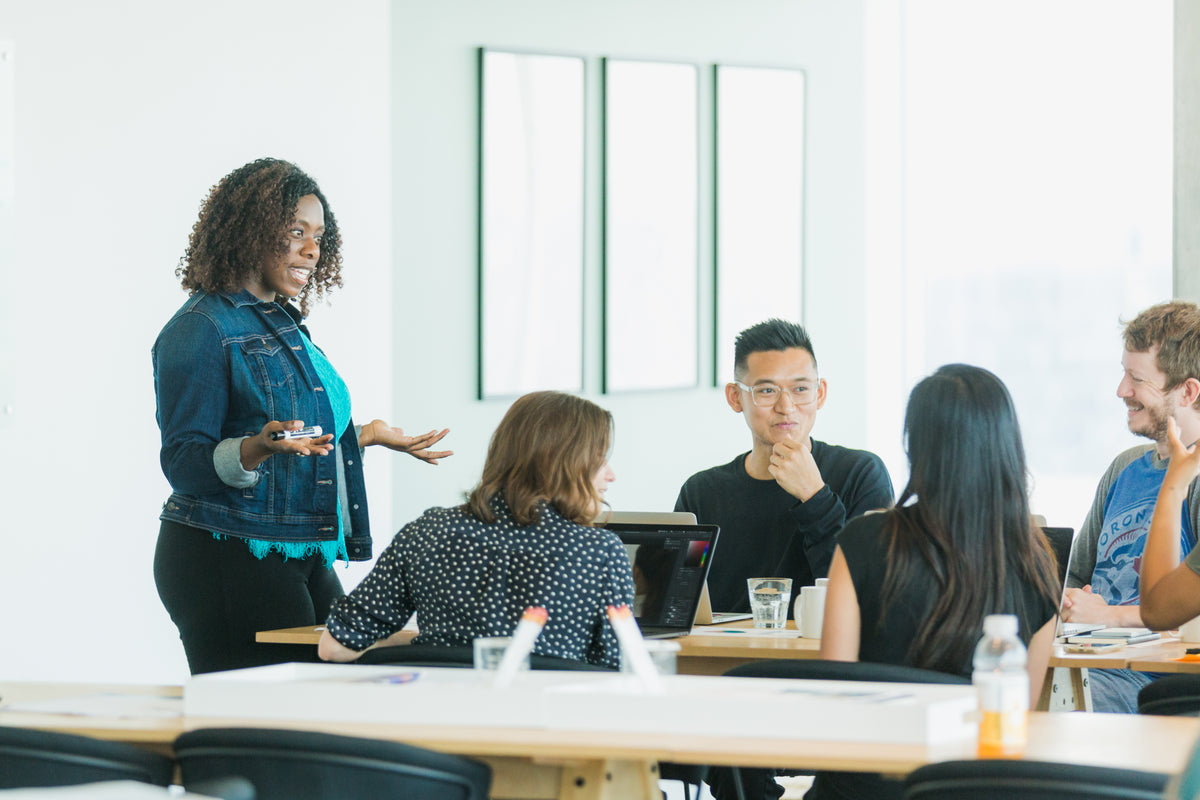 A woman presenting to a team seated around a table